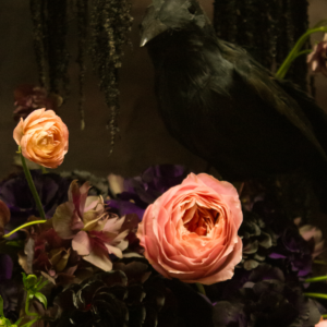 Gothic Halloween floral arrangement with dark blooms, a black raven, and antique-style urn for party decor in Los Angeles.