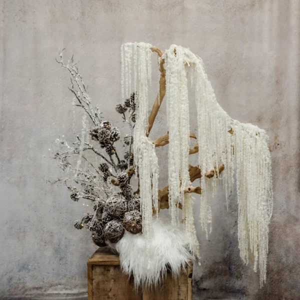 A sculptural winter display with ivory textures, frosted pinecones, shimmering branches, and faux fur accents, perfect for holiday or seasonal décor.