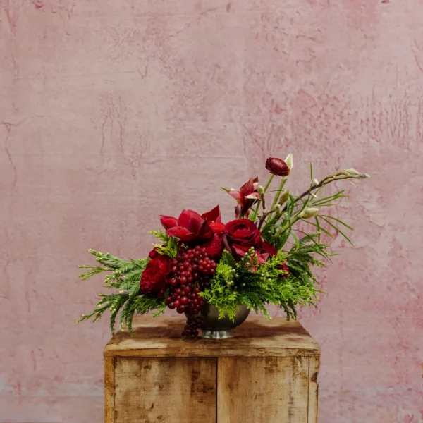 A bold arrangement featuring ruby amaryllis, rich blooms, winter berries, and textured greenery, part of the Celestial Yule Collection.