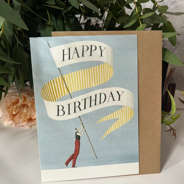 Illustrated birthday card featuring a figure holding a pole with a yellow and white striped banner that reads ‘Happy Birthday,’ set against a soft blue background.