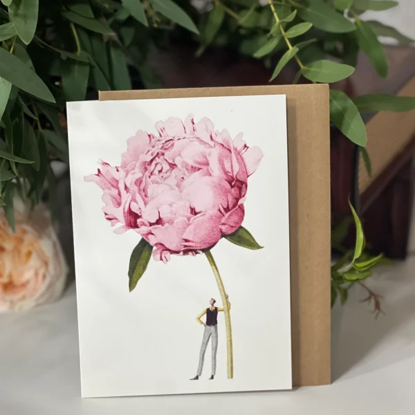 Greeting card showcasing a large pink peony flower held by a small, minimalist figure, with a clean white background